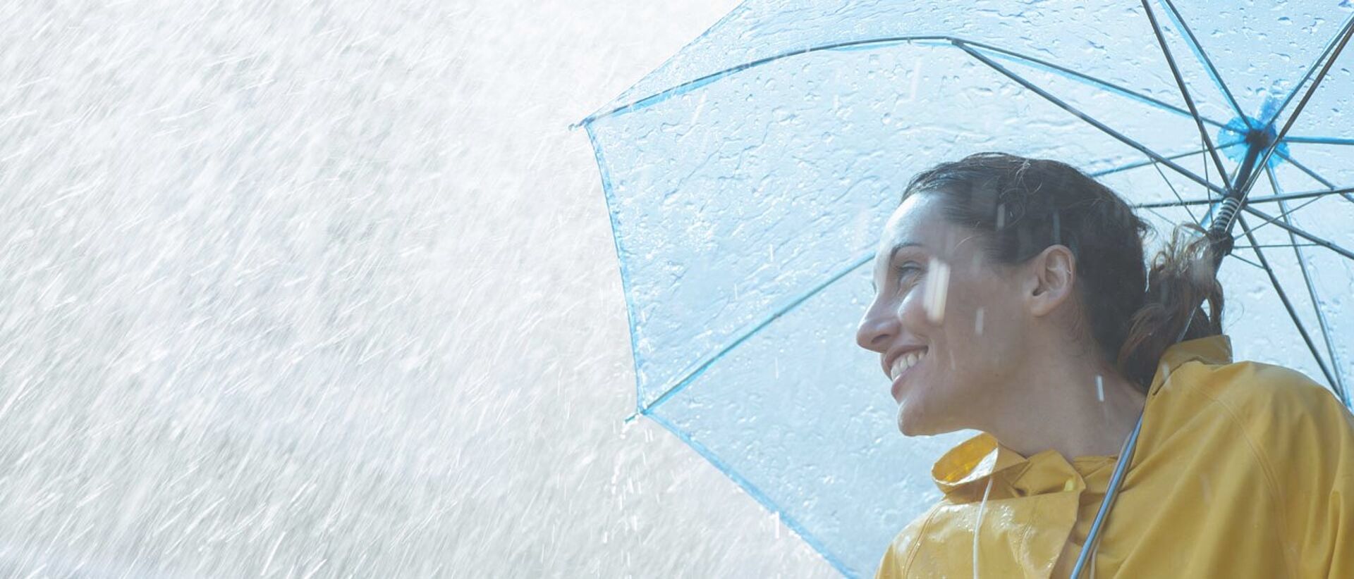 Mujer con impermeable y paraguas probados con PFAS bajo la lluvia