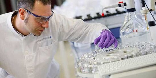 Técnico de laboratorio sosteniendo un tubo en el laboratorio de Hohenstein