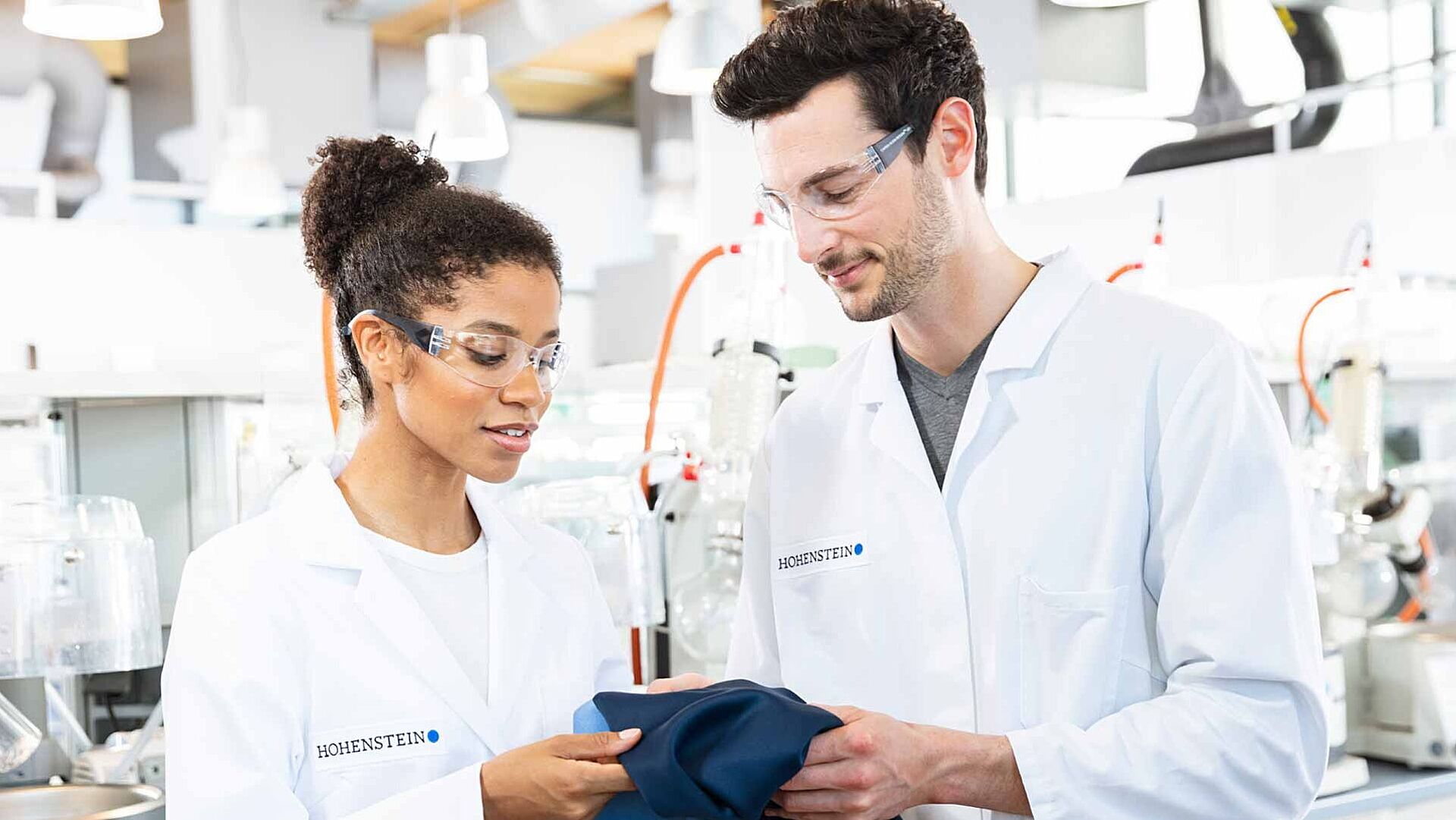 Dos técnicos de laboratorio de Hohenstein analizando un textil azul