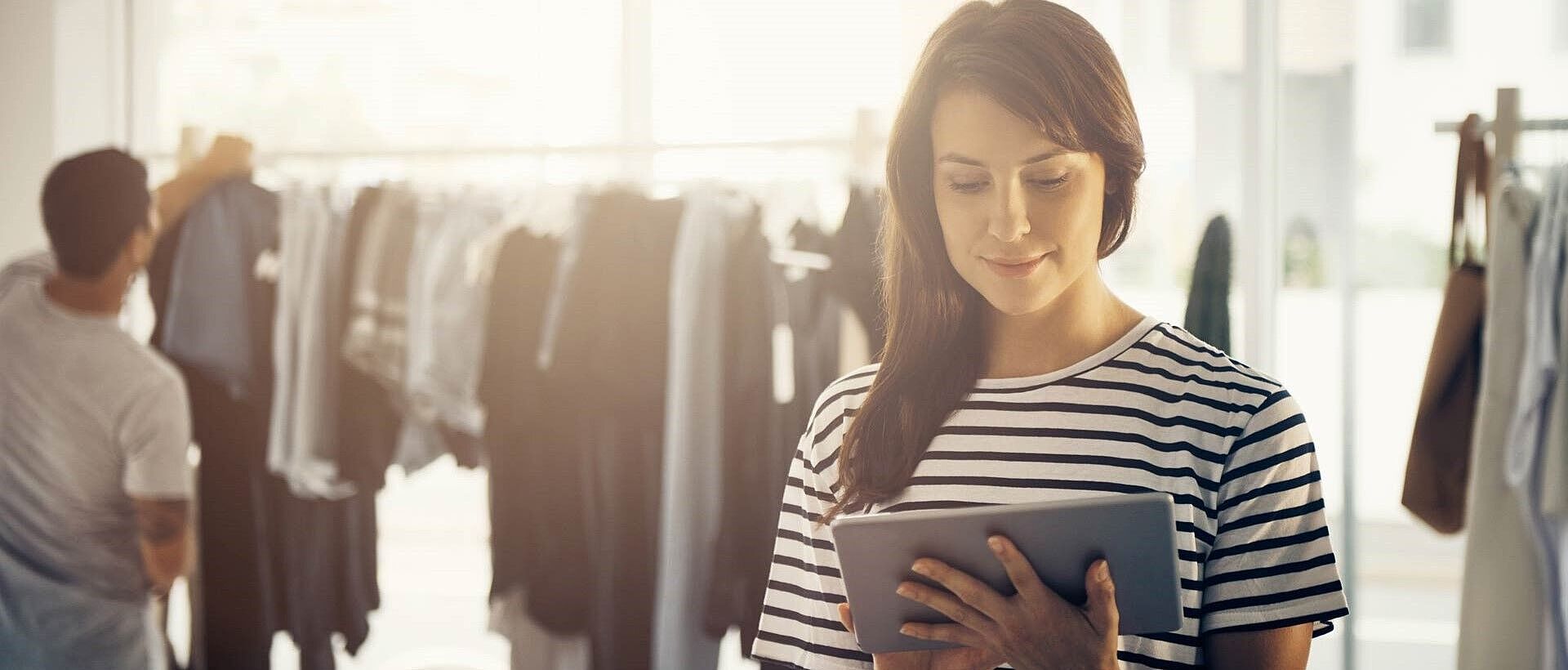 Diseñadora de ropa con camisa a rayas usando una tableta