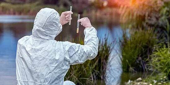 Auditor tomando muestras de aguas residuales de un arroyo cerca de una planta textil