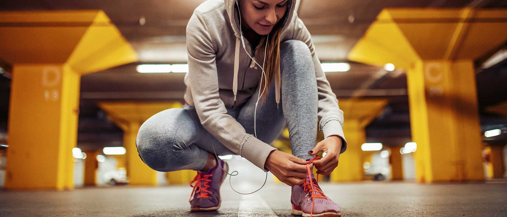 Mujer inclinada para atar el zapato deportivo