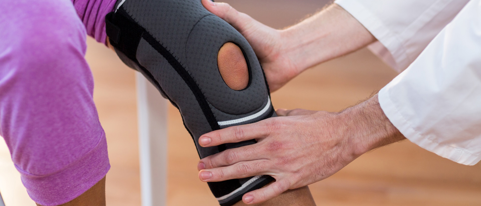 Prueba de dispositivo médico de rodillera en paciente Paciente con rodillera sentado con un experto en dispositivos médicos sosteniendo la rodilla