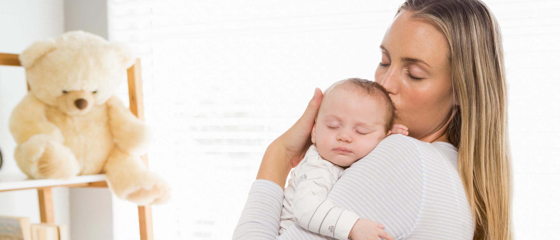 Madre con su bebé cerca del rostro en un dormitorio con luz suave