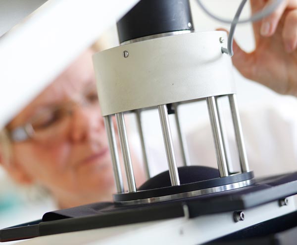 Pruebas de desempeño físico en batas y campos quirúrgicos Técnico realizando prueba de resistencia física en material textil quirúrgico