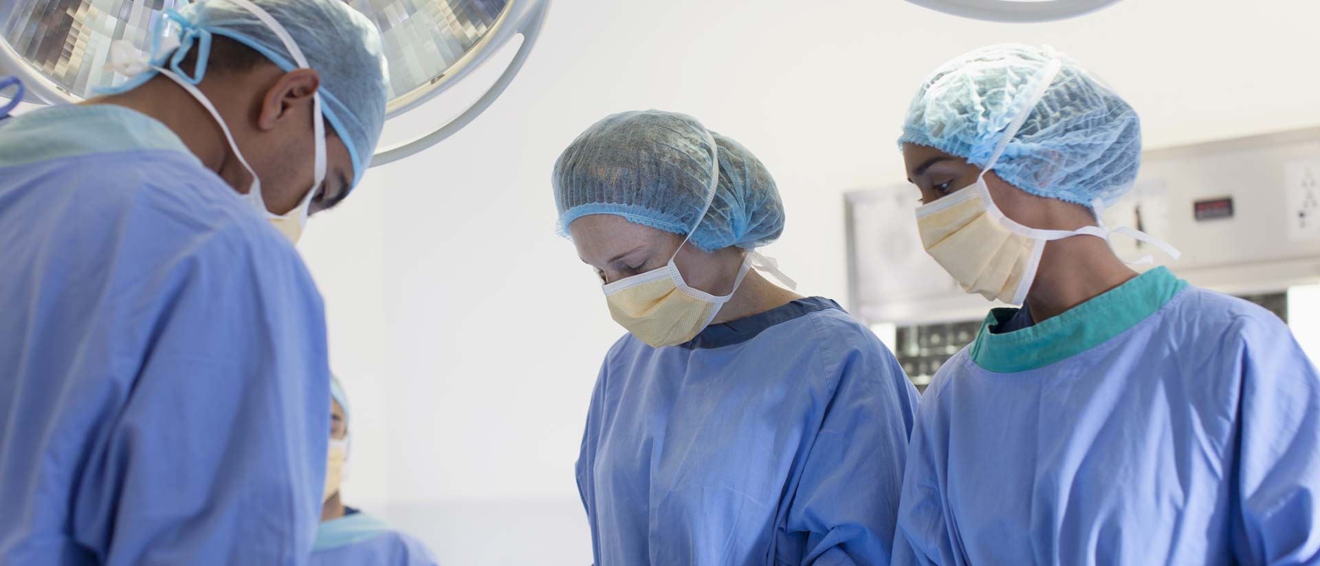 Requisitos de prueba para batas y campos quirúrgicos Grupo de cirujanos con mascarillas y batas estériles en un quirófano