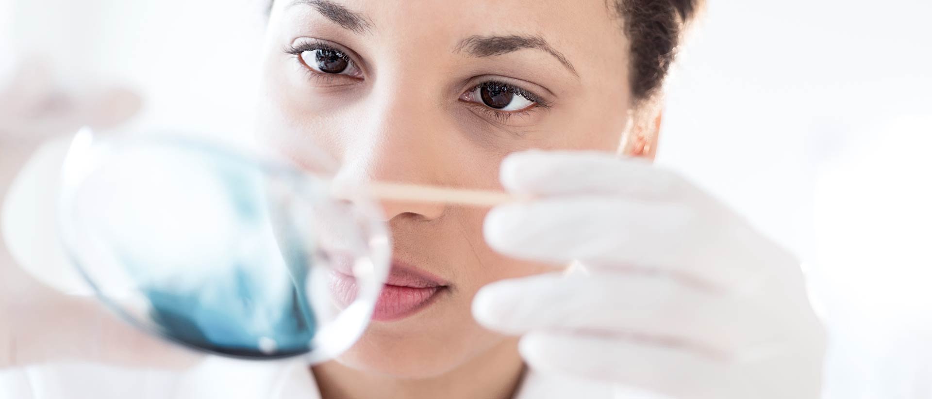 Químico sosteniendo un plato con productos químicos azules en el laboratorio en pruebas en Hohenstein