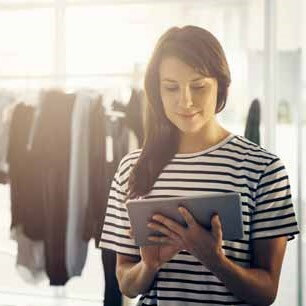 Diseñadora de ropa con camisa a rayas usando una tableta