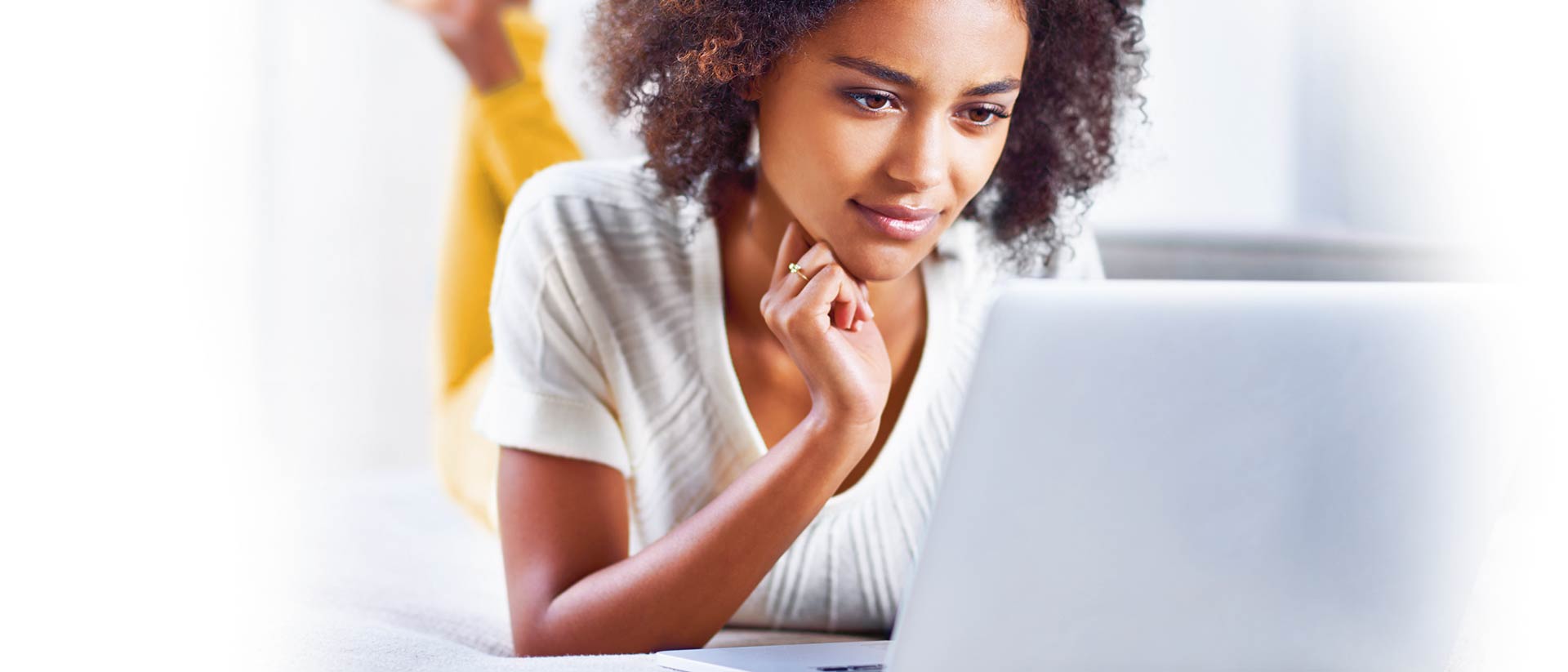 Mujer con camisa blanca y pantalones amarillos mirando la computadora