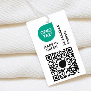 OEKO-TEX® MADE IN GREEN Etiqueta colgante en una pila de toallas blancas