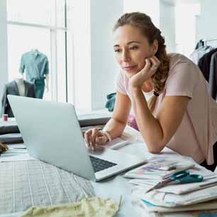 Mujer trabajando en la computadora portátil en el estudio de diseño de prendas de vestir