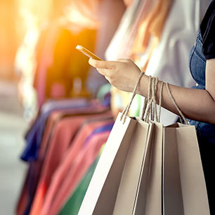 Comprador sosteniendo teléfono y bolsas
