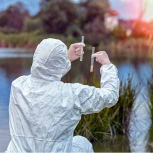 Experto en EPP recolectando muestras de agua cerca de una fábrica textil