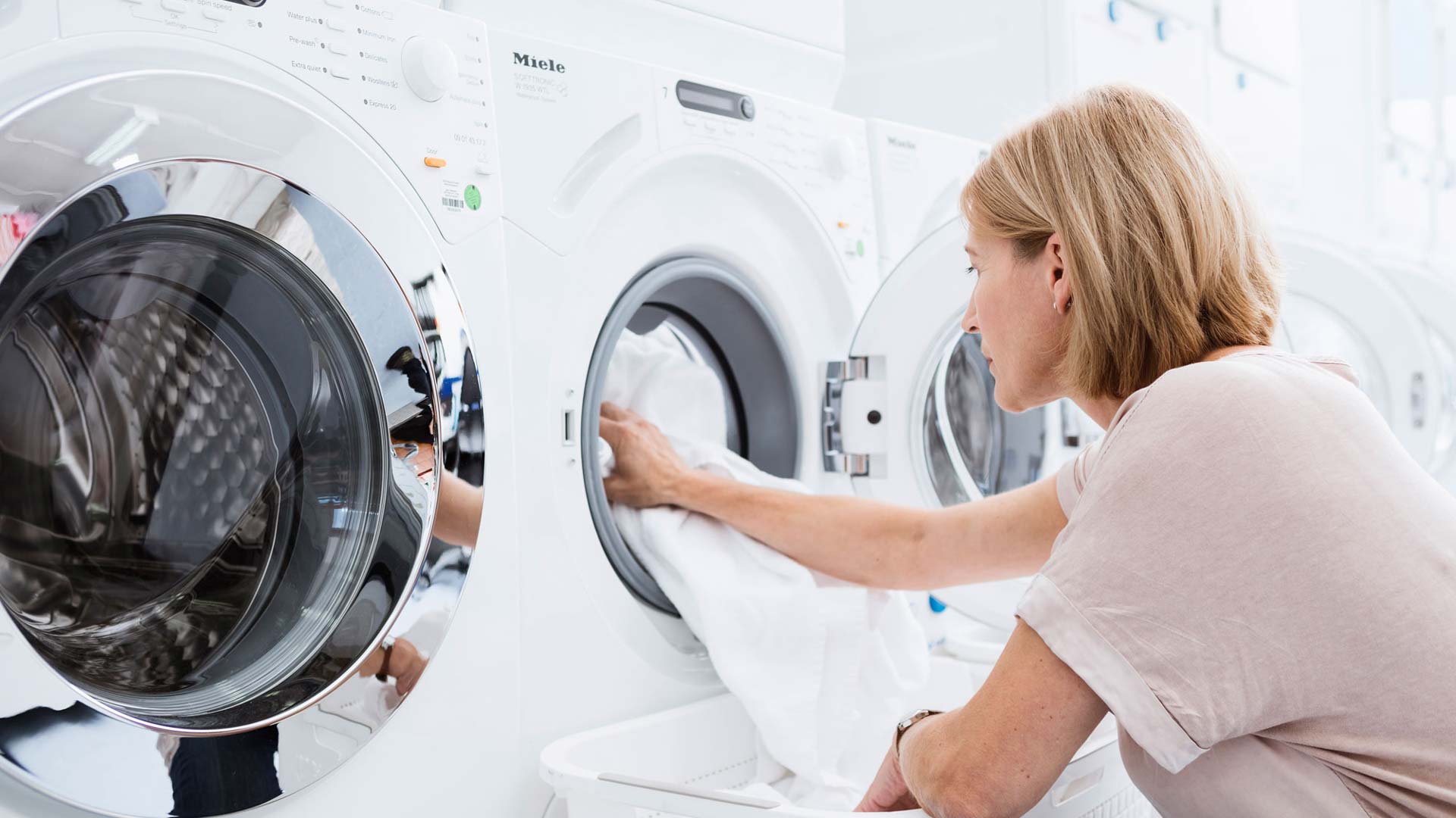 Mujer poniendo una toalla en una lavadora de prueba de lavado