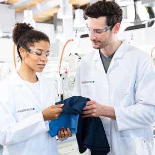 Dos técnicos de laboratorio Hohenstein analizando un textil azul