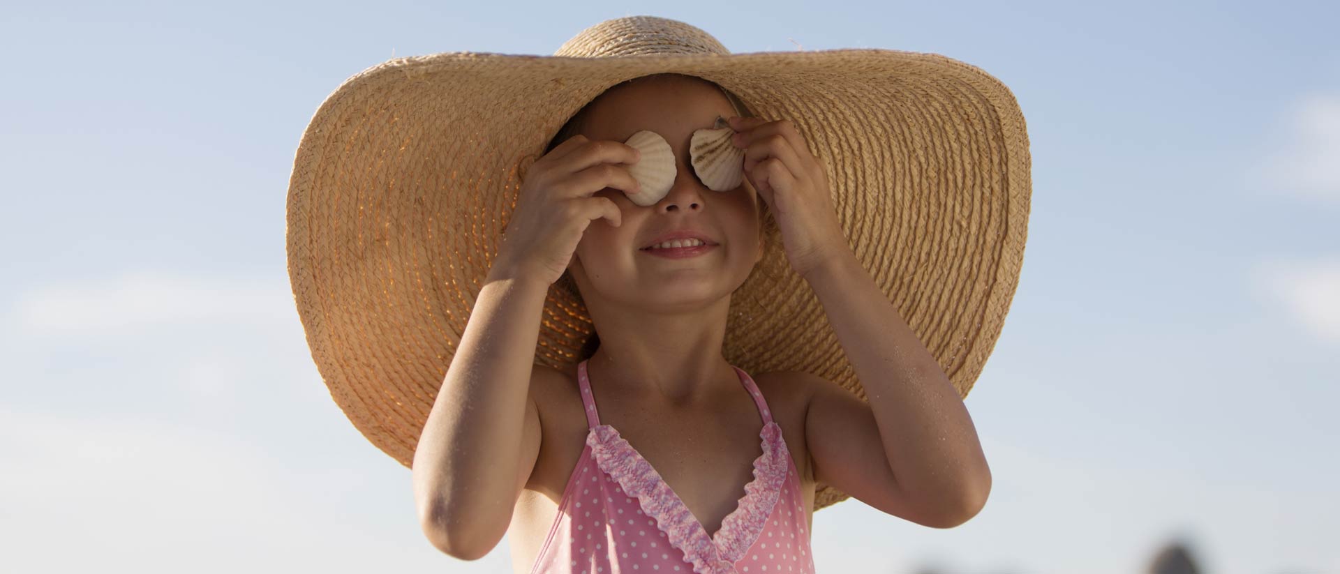 Chica con gran sombrero para el sol y traje de baño rosa en un día soleado