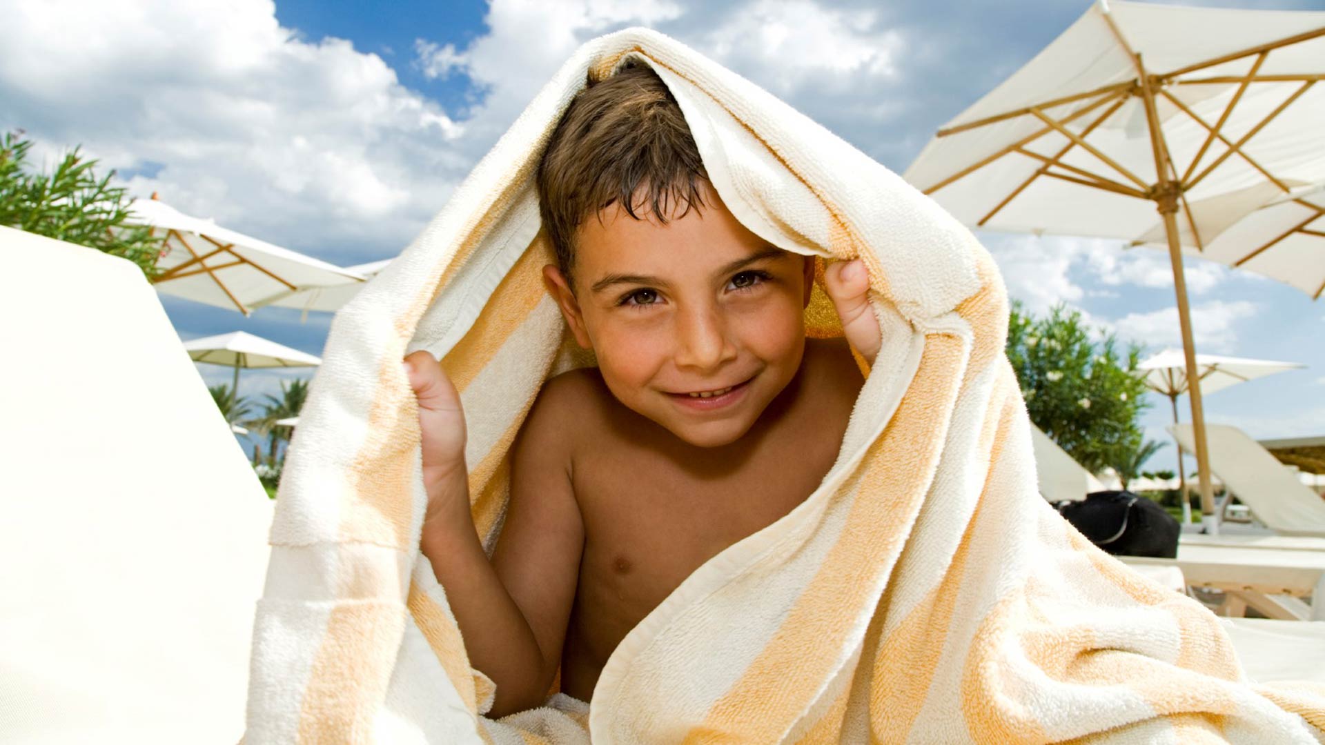 Niño bajo una toalla a rayas en un día soleado